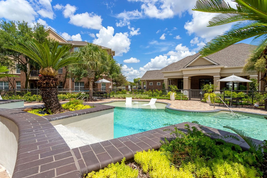a swimming pool with the resident clubhouse in the background at Madison on the Meadow, Stafford, TX, 77477