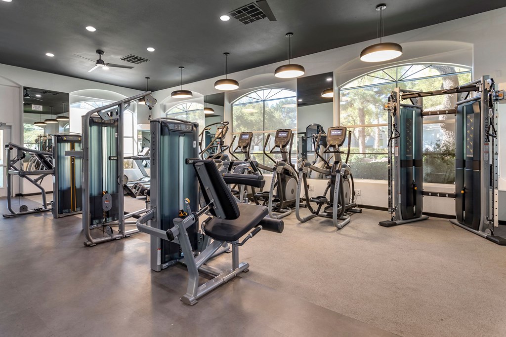 a gym with cardio machines and weights in a building with windows at Mirasol Apartments, Las Vegas, NV 89119