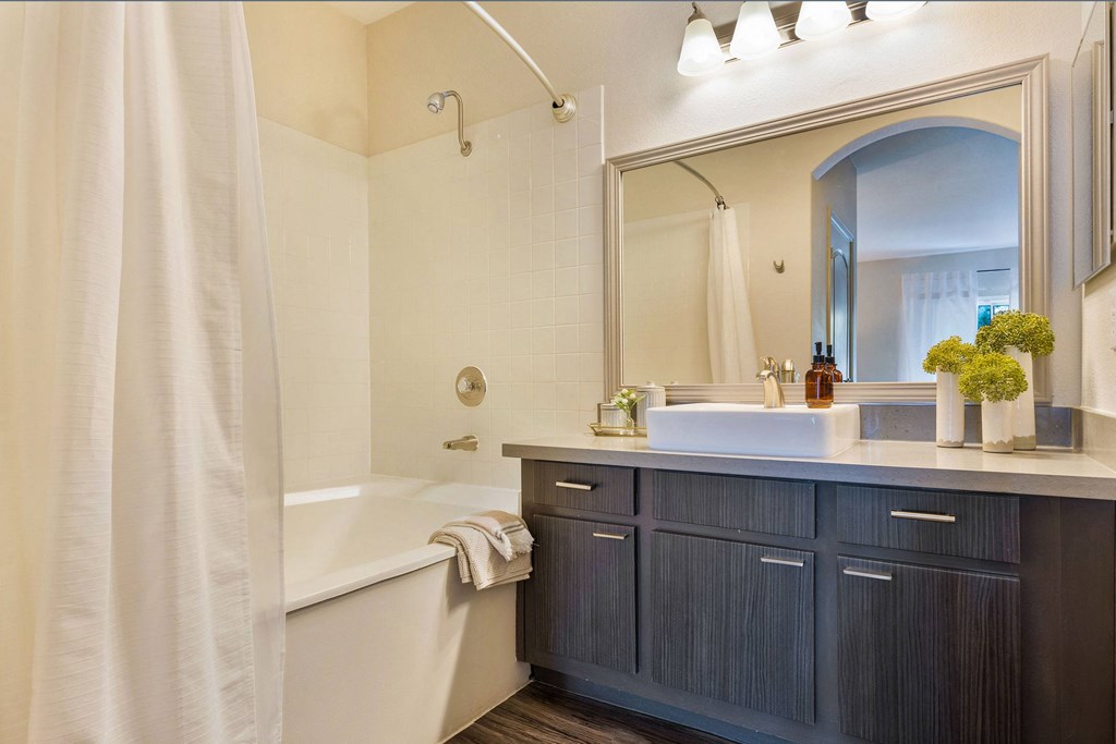 a bathroom with a tub and a sink and a mirror at Mirasol Apartments, Las Vegas