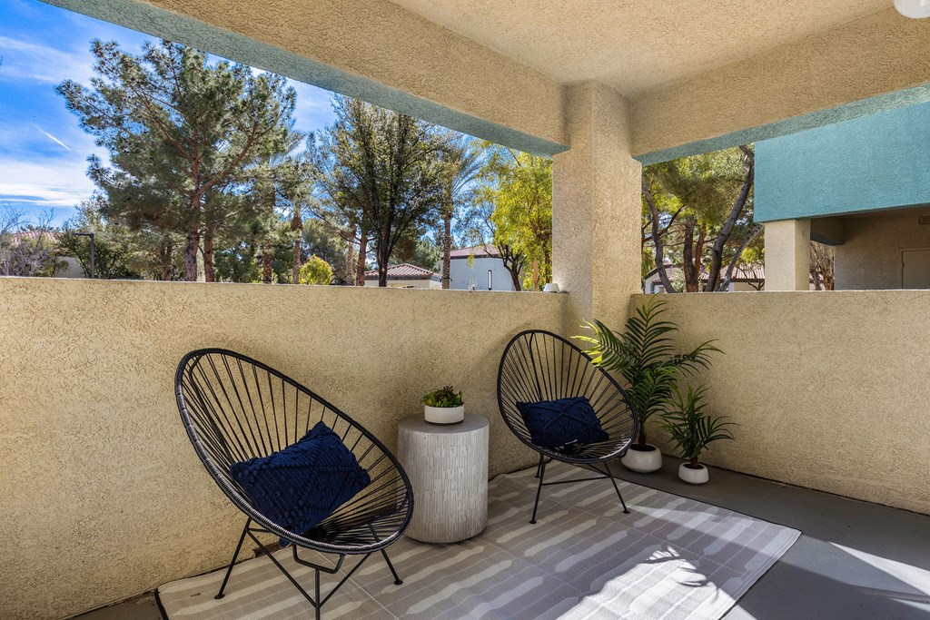 a patio with two chairs and a plant on a balcony at Mirasol Apartments, Las Vegas, NV