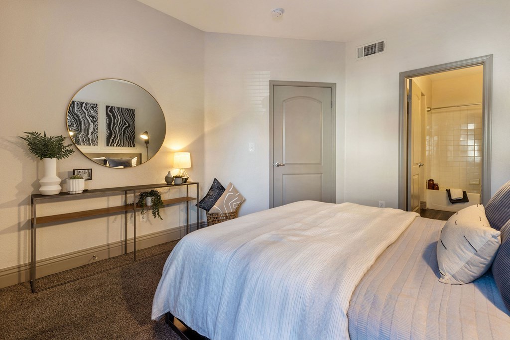 a bedroom with a large white bed and a mirror at Mirasol Apartments, Las Vegas