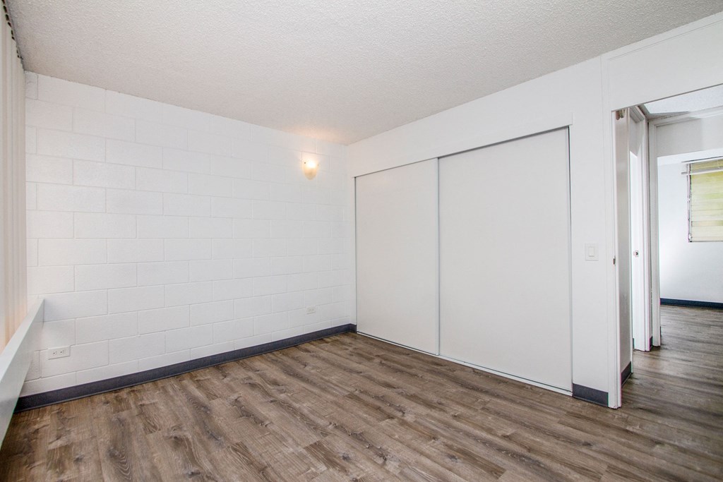 an empty living room with white walls and wood flooring at Palms of Kilani Apartments, Wahiawa, 96786