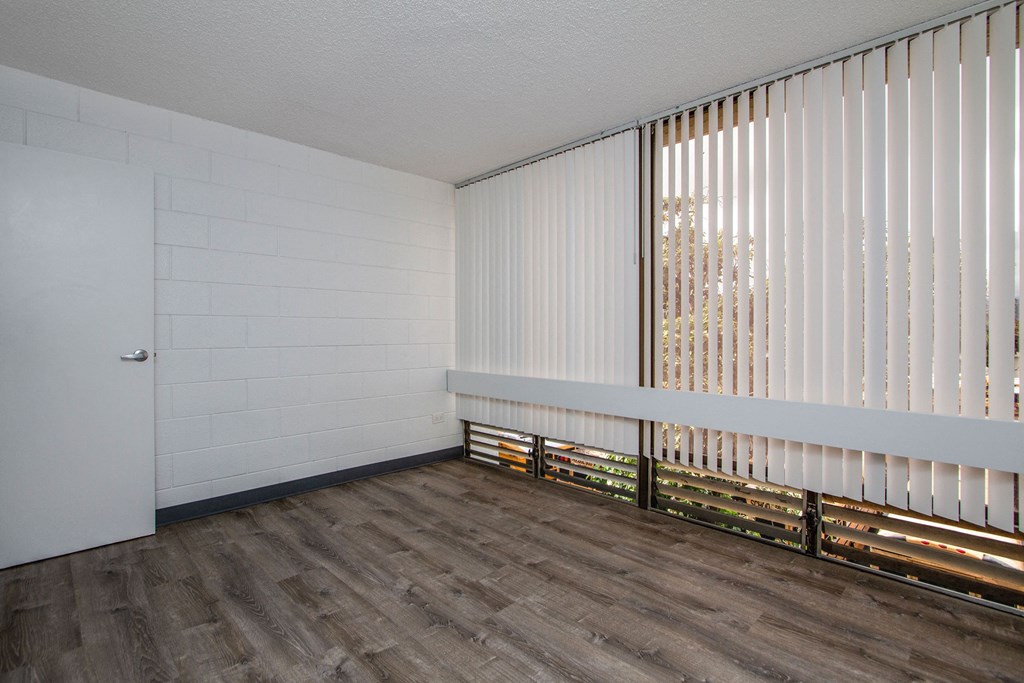 an empty living room with white blinds on the window at Palms of Kilani Apartments, Hawaii