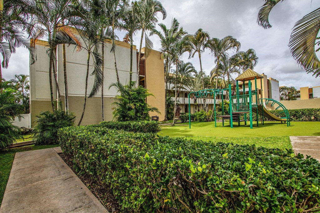 a playground with palm trees in front of a building at Palms of Kilani Apartments, Wahiawa, HI, 96786