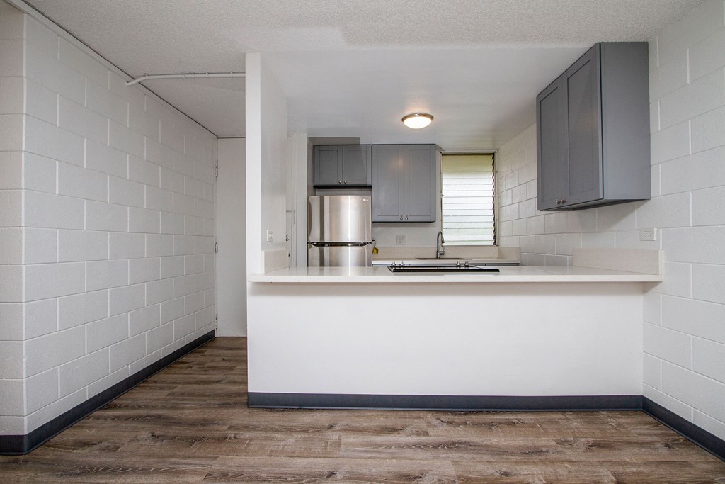 a kitchen with a counter and a refrigerator and a sink at Palms of Kilani Apartments, Wahiawa, HI