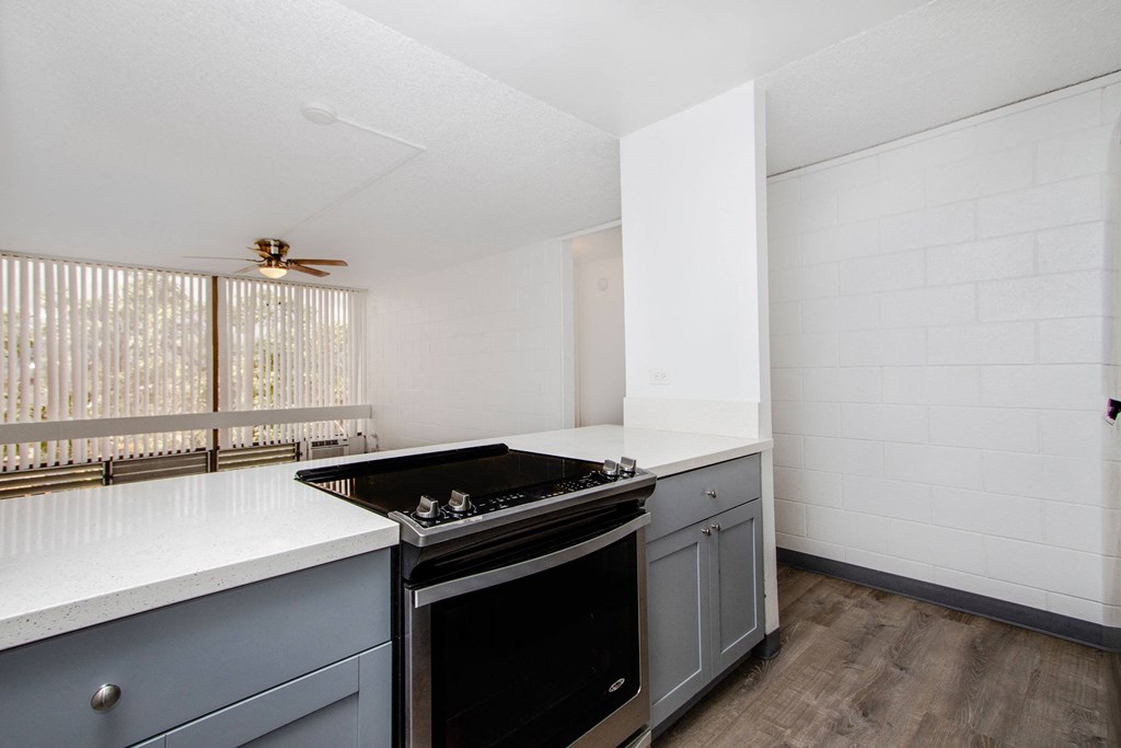 an empty kitchen with white counter tops and a black stove at Palms of Kilani Apartments, Hawaii, 96786