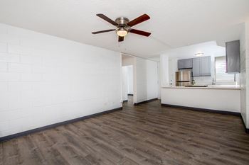 an empty living room with a ceiling fan and a kitchen at Palms of Kilani Apartments, Wahiawa, 96786