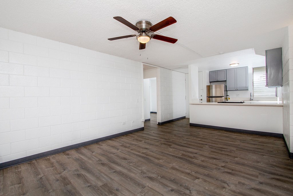 an empty living room with a ceiling fan and a kitchen at Palms of Kilani Apartments, Wahiawa, HI, 96786