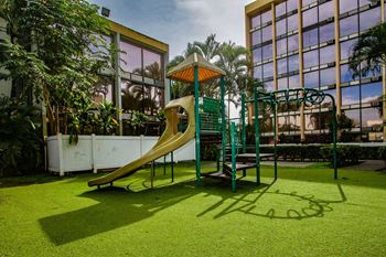 a playground with a slide next to a building at Palms of Kilani Apartments, Wahiawa, HI
