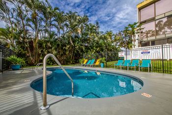 a swimming pool at a hotel with palm trees at Palms of Kilani Apartments, Wahiawa, HI, 96786