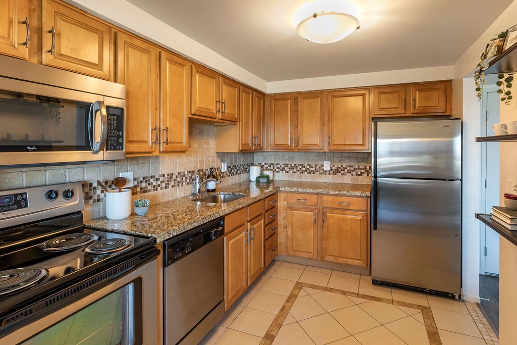 a kitchen with stainless steel appliances and wooden cabinets at The Rays at Vegas Towers Apartments, Nevada