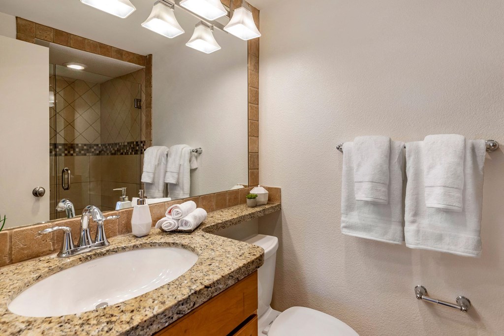 a bathroom with a sink and a toilet and a mirror at The Rays at Vegas Towers Apartments, Las Vegas