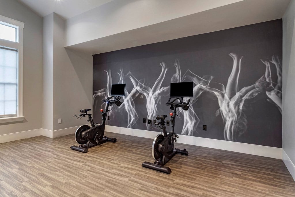 a home gym with two exercise bikes in front of a wall with art on it at Reserve by the Lake, Houston, Texas