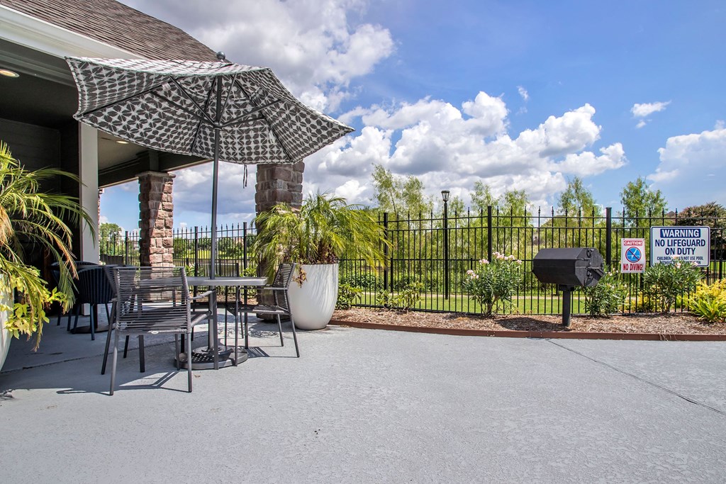 a patio with a table and chairs and an umbrella and a grill at Reserve by the Lake, Houston, TX, 77084