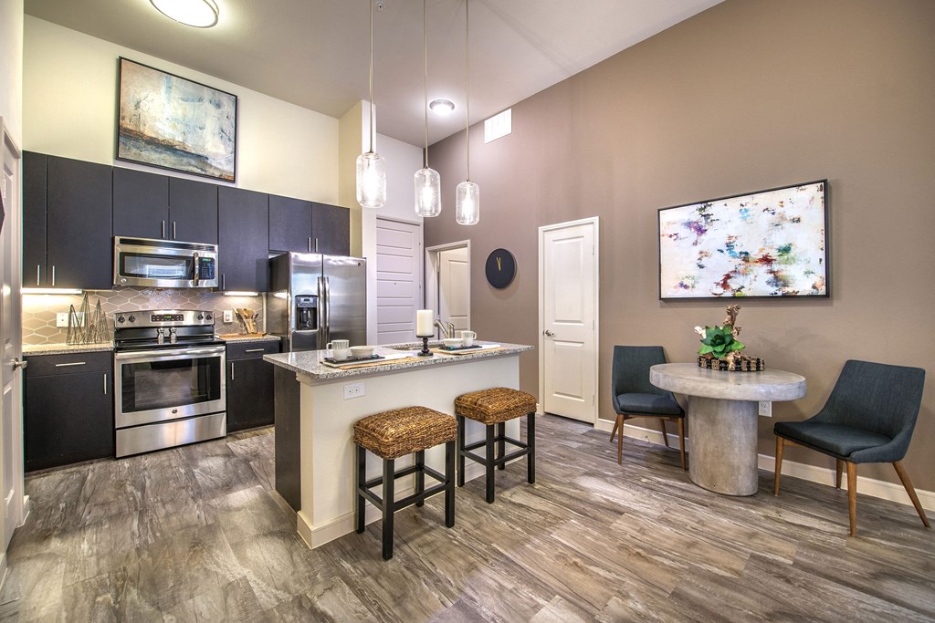 a kitchen with stainless steel appliances and a bar with stools at South Side Flats, Dallas