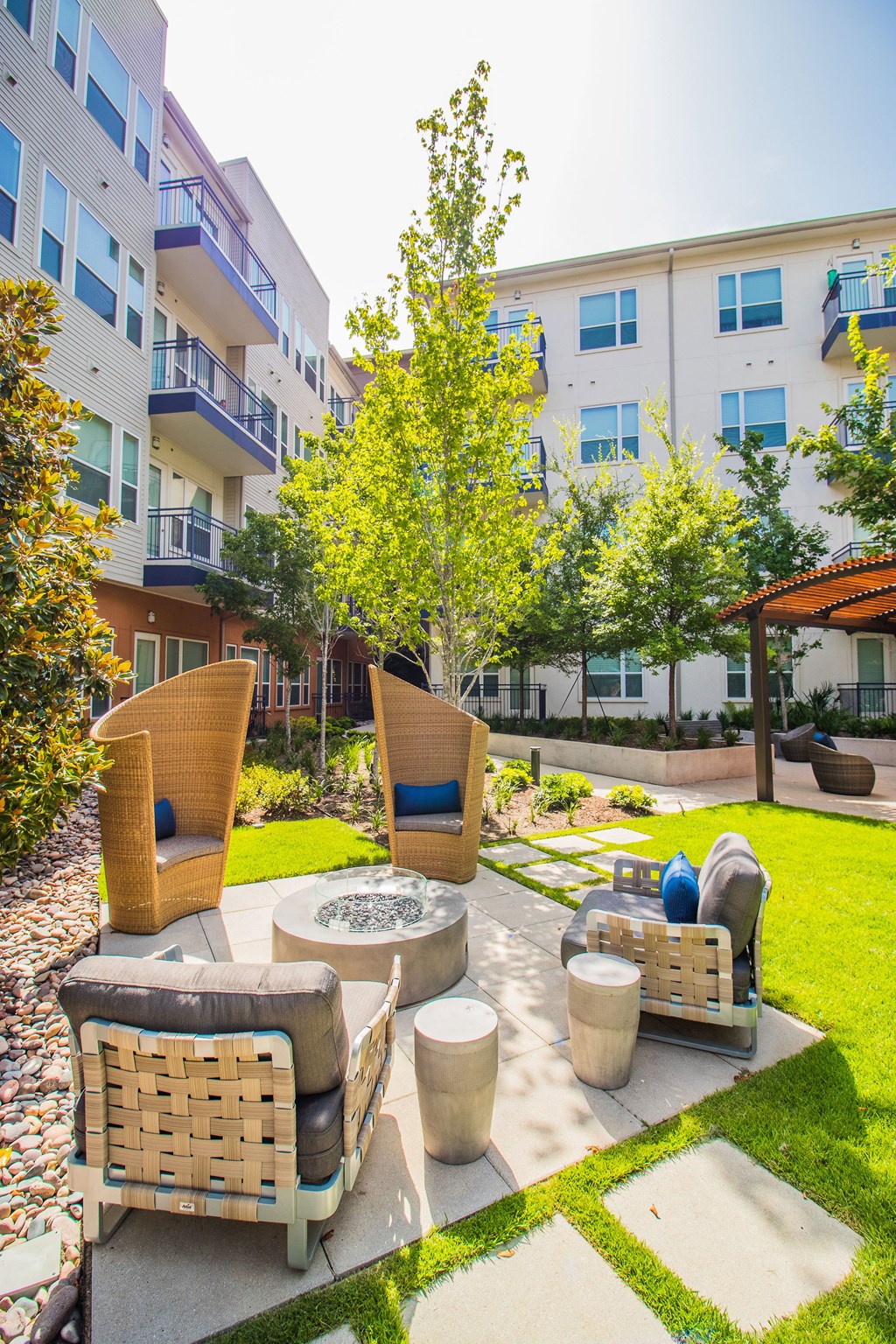 a patio with chairs and a fire pit in front of an apartment building at South Side Flats, Texas, 75215