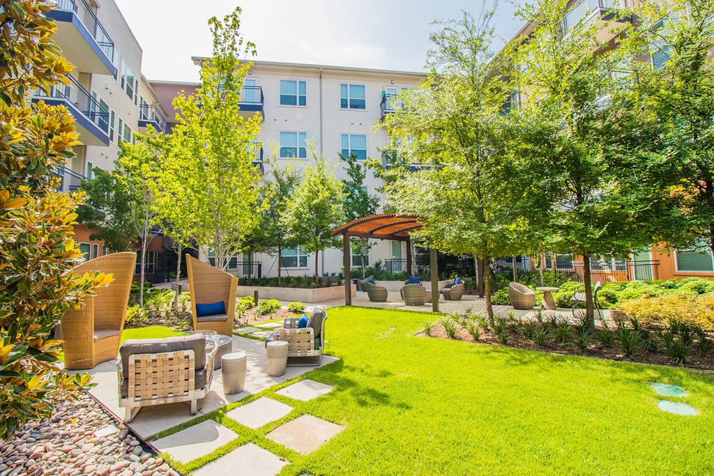 a yard with furniture and trees in front of an apartment building at South Side Flats, Dallas, Texas