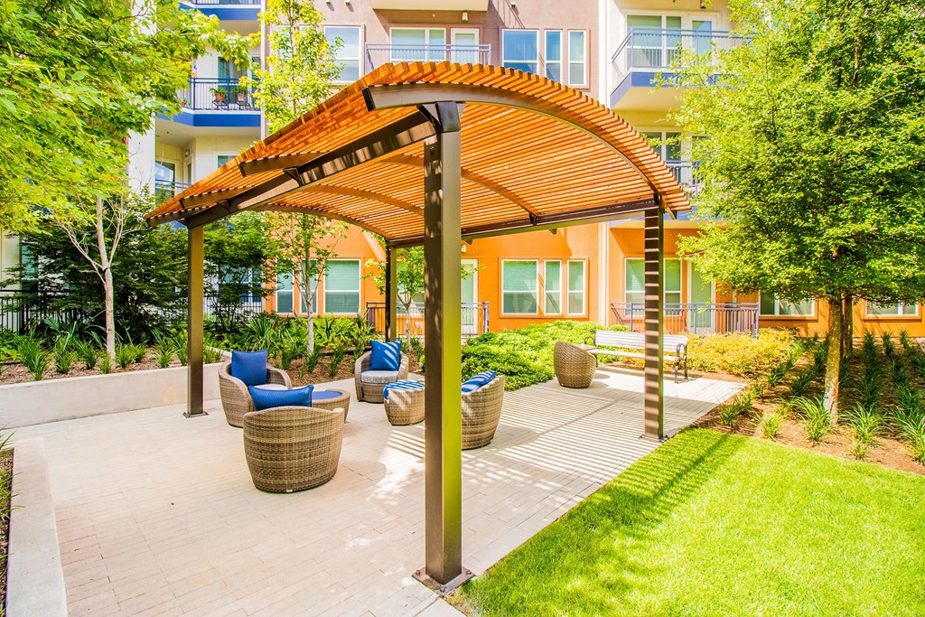 a patio with chairs and a pergola in front of an apartment building at South Side Flats, Dallas, TX, 75215