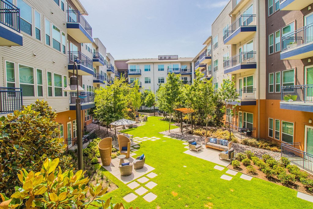 an apartment courtyard with grass and trees in the middle of it at South Side Flats, Dallas, TX