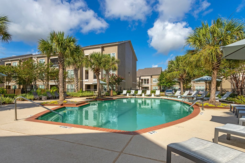 a swimming pool with palm trees and a building in the background at Summerwind, Texas, 77584