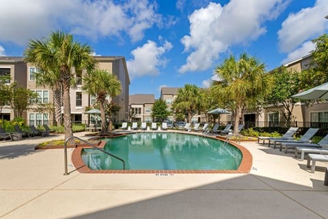 a swimming pool with palm trees in front of a building at Summerwind, Pearland