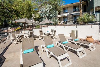 a patio with chairs and umbrellas in front of a building at Sunset Winds Apartments, Nevada, 89014