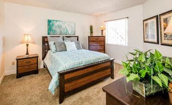 a bedroom with a bed and a potted plant at Sunset Winds Apartments, Henderson, NV 89014