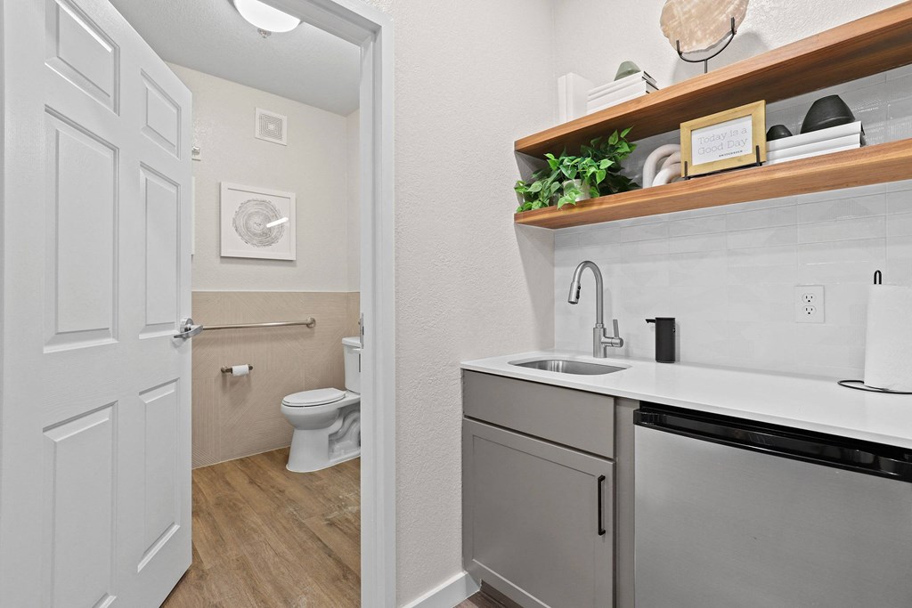 a bathroom with a sink and a toilet and a laundry room with a door open at Switchback on Platte Apartments, Littleton, CO 80120