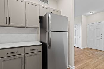 an empty kitchen with a refrigerator and white cabinets at Switchback on Platte Apartments, Colorado