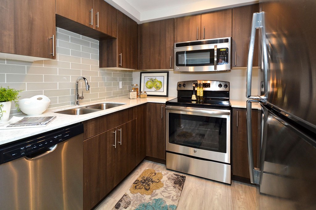 a kitchen with stainless steel appliances and wooden cabinets  at Apartments at Denver Place, Denver, 80202