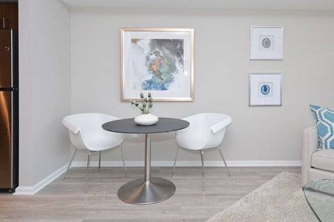 a dining room with a table and chairs and a painting on the wall  at Apartments at Denver Place, Denver, CO