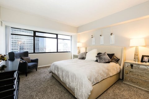 a bedroom with a large bed and a large window at Apartments at Denver Place, Denver, CO 80202