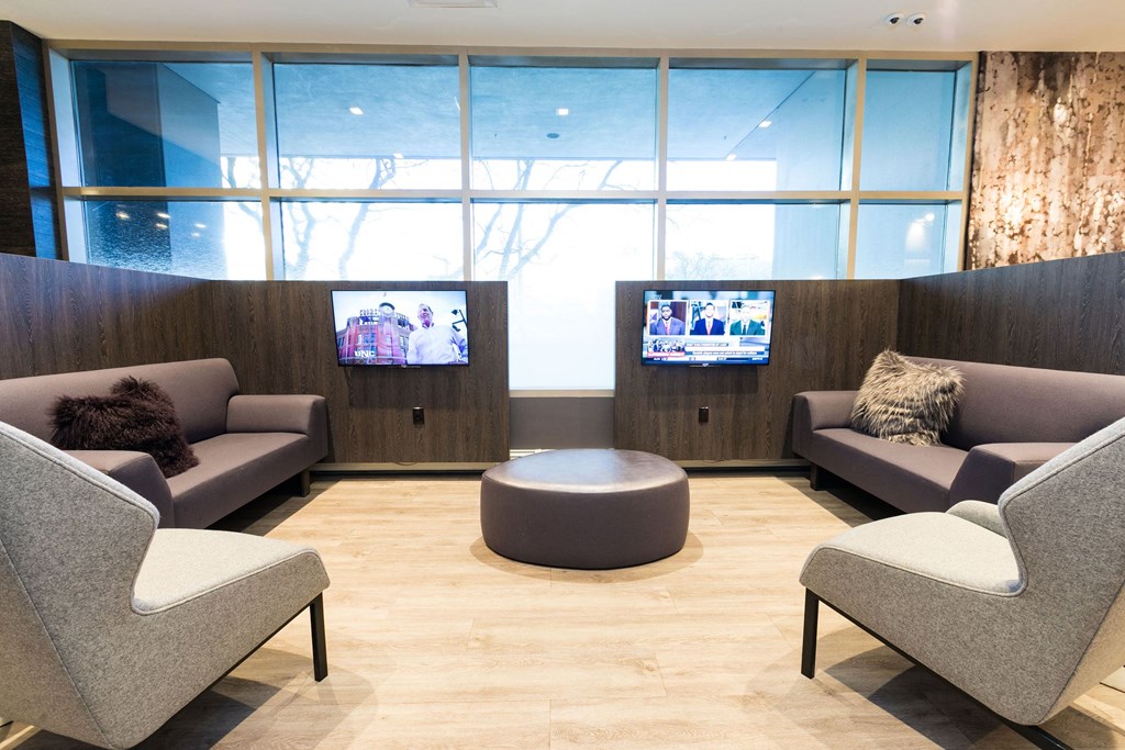 a waiting room with couches and chairs and two televisions at Apartments at Denver Place, Denver