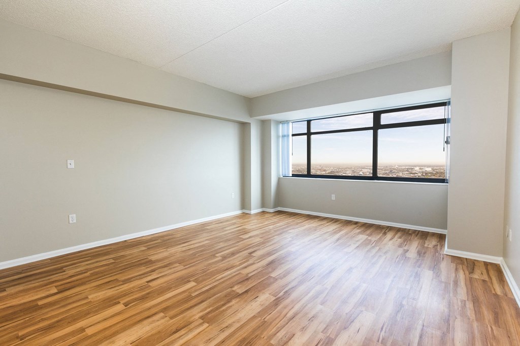 an empty living room with wood floors and a window at Apartments at Denver Place, Denver, CO