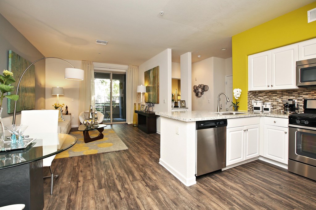 A modern kitchen with white cabinets and a wooden floor at The Kitt at Warner Center Apartments, Woodland Hills