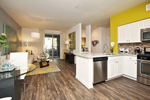 A modern kitchen with white cabinets and a wooden floor at The Kitt at Warner Center Apartments, Woodland Hills