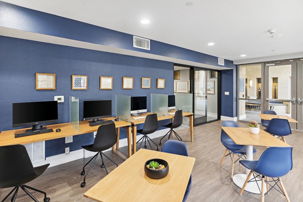 A room with blue walls and wooden tables with chairs at The Kitt at Warner Center Apartments, Woodland Hills, CA