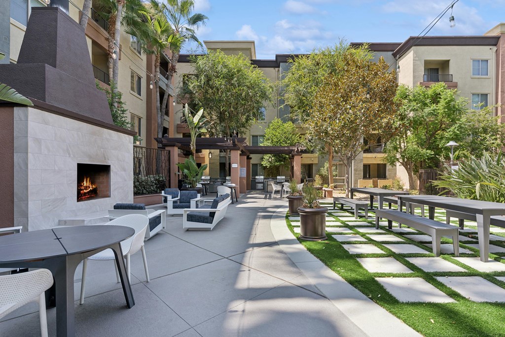 A patio with a fireplace and chairs. at The Kitt at Warner Center Apartments, Woodland Hills, CA, 91303
