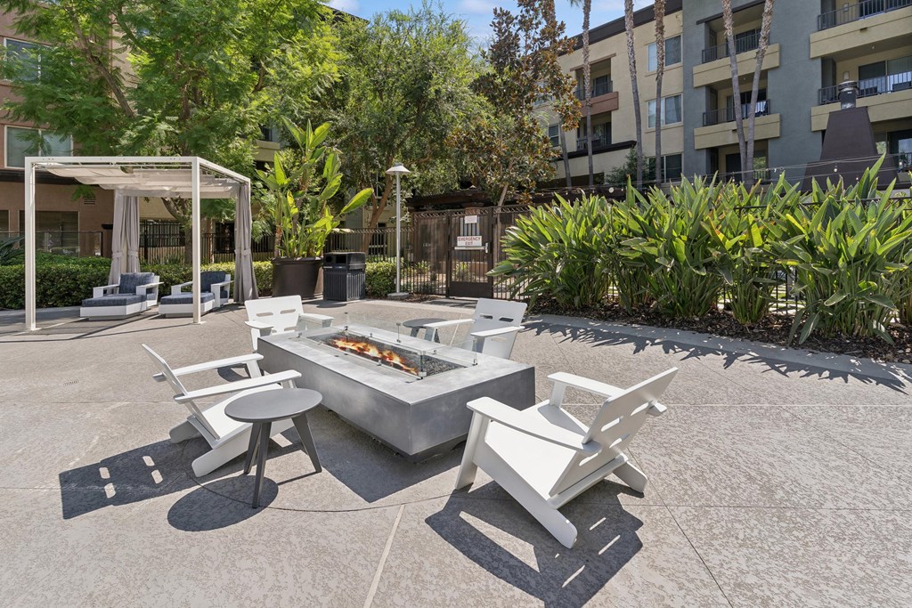 A white outdoor barbecue grill with chairs and a table is set up in a courtyard at The Kitt at Warner Center Apartments, Woodland Hills, California