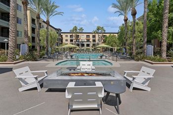 A pool surrounded by palm trees and chairs. at The Kitt at Warner Center Apartments, Woodland Hills