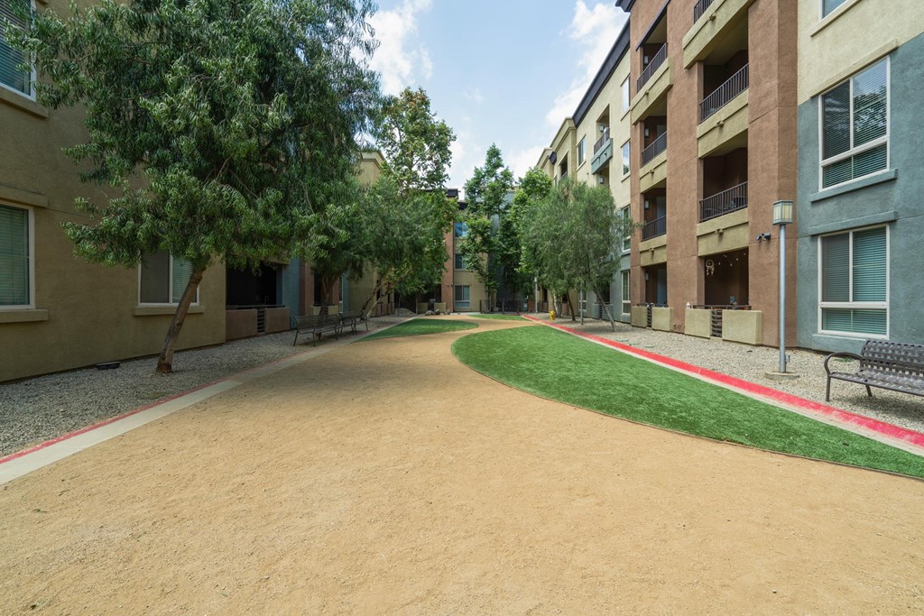 A long, narrow, dirt pathway leads between two rows of apartment buildings at The Kitt at Warner Center Apartments, Woodland Hills, California