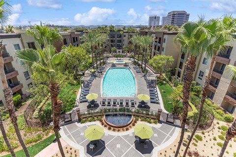 A pool surrounded by palm trees and umbrellas at The Kitt at Warner Center Apartments, Woodland Hills 91303