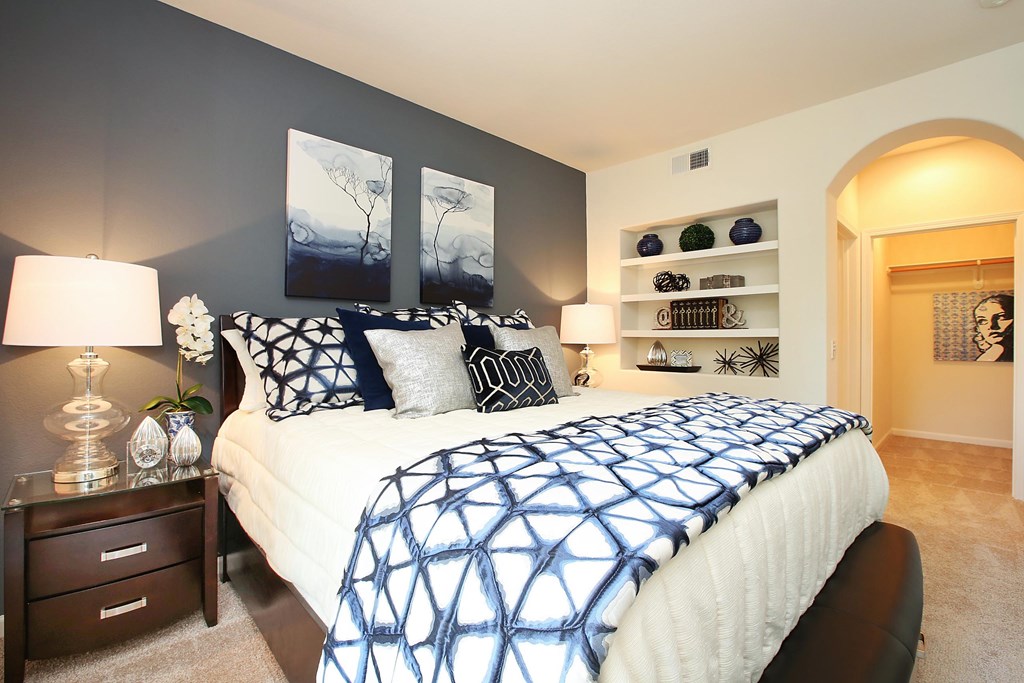 A bedroom with a bed, nightstand, and wall art at The Kitt at Warner Center Apartments, Woodland Hills, CA