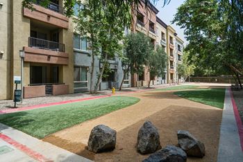 A large rock sits in the middle of a dirt path at The Kitt at Warner Center Apartments, California