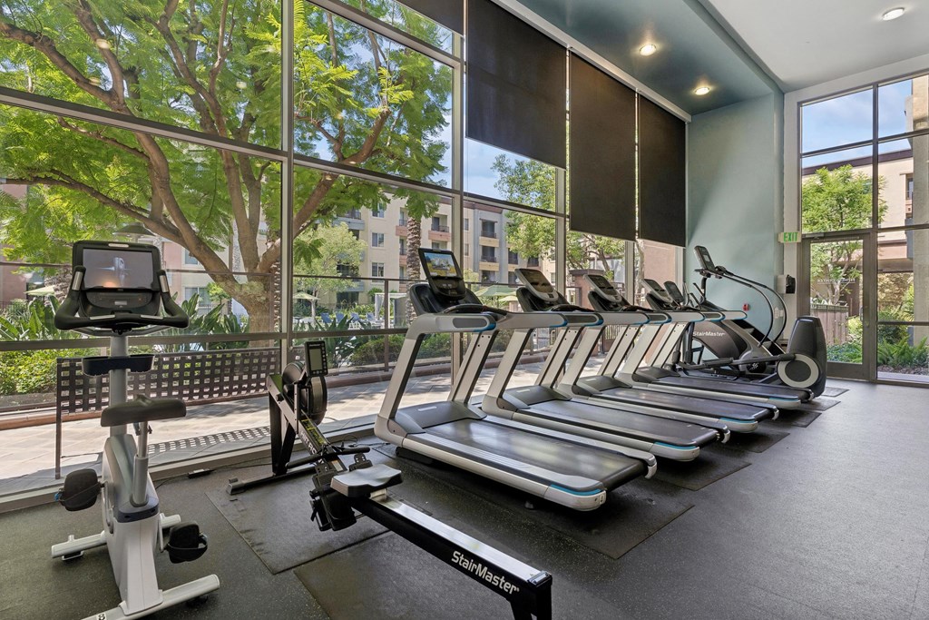 A gym with treadmills, elliptical machines, and a rowing machine at The Kitt at Warner Center Apartments, Woodland Hills, CA, 91303