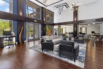 A modern living room with a large rug and a long couch. at The Kitt at Warner Center Apartments, Woodland Hills, CA