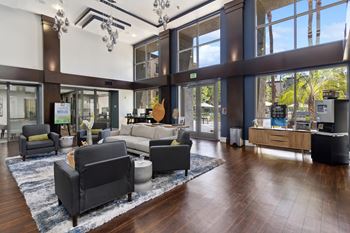 A large room with a lot of furniture and a view of trees outside the windows. at The Kitt at Warner Center Apartments, Woodland Hills, California