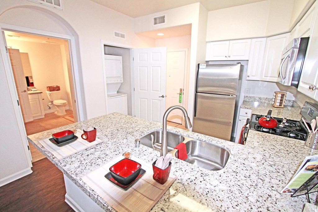 A kitchen with a granite counter top and stainless steel appliances at The Kitt at Warner Center Apartments, Woodland Hills 91303