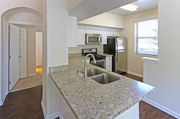 A kitchen with granite countertops and stainless steel appliances at The Kitt at Warner Center Apartments, Woodland Hills, CA