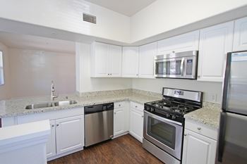 A kitchen with white cabinets and stainless steel appliances. at The Kitt at Warner Center Apartments, Woodland Hills, CA, 91303